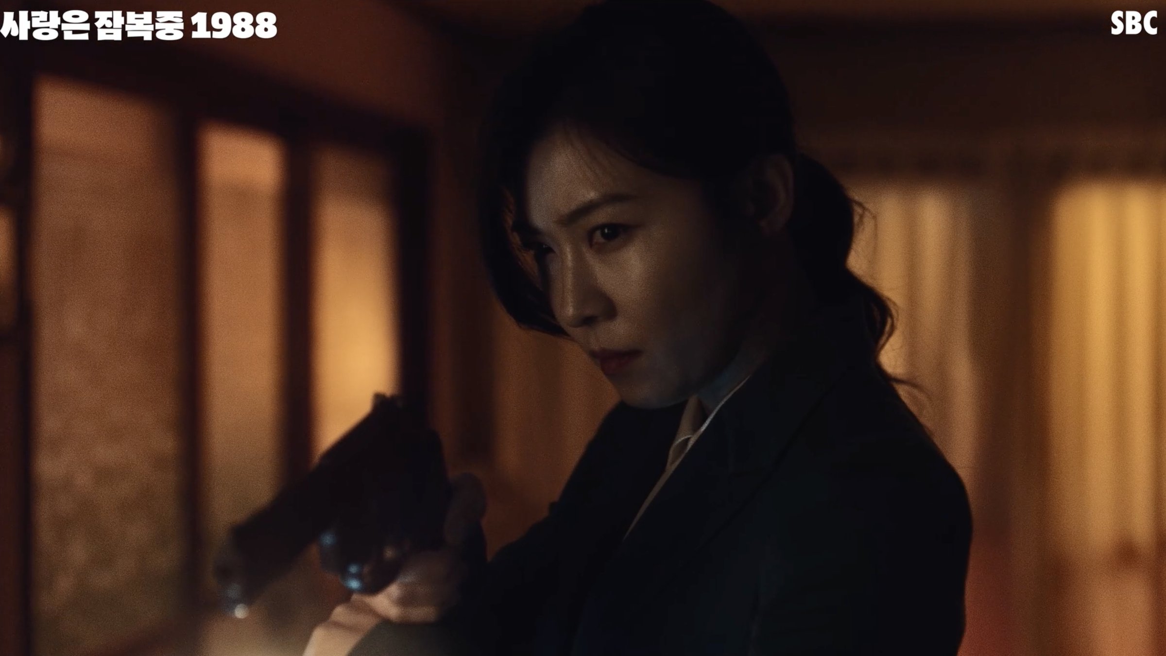 A detective takes aim with a pistol in a dark hallway, in one of the show's in-world K-dramas