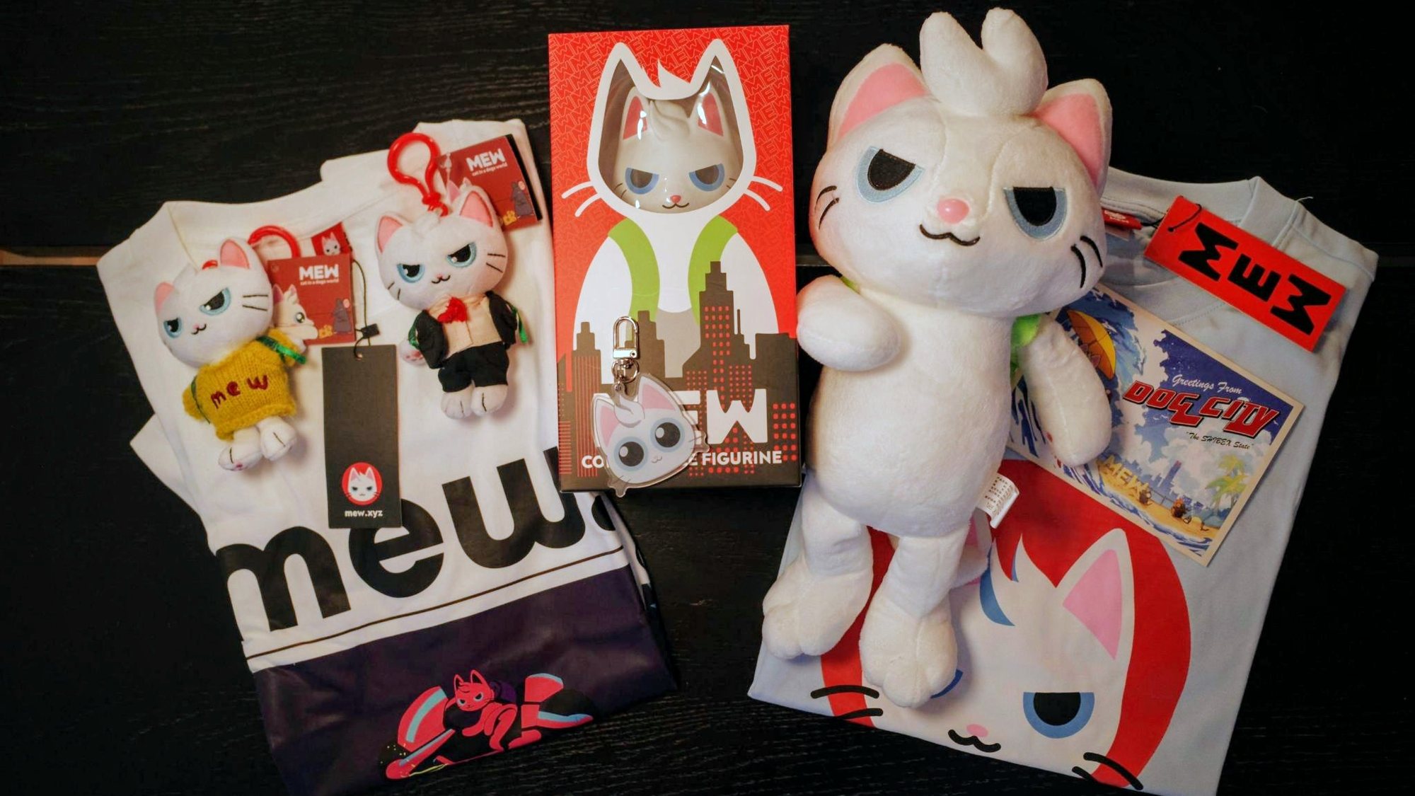 Mew merchandise: plush keychains, a boxed collectible figurine, a large plush, T-shirts and a Dog City postcard